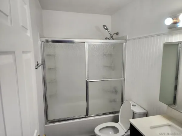 a bathroom with a shower sink mirror and toilet