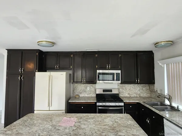 a kitchen with granite countertop a refrigerator stove and sink