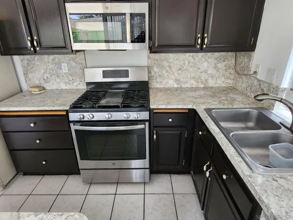 a kitchen with granite countertop a sink stove and cabinets