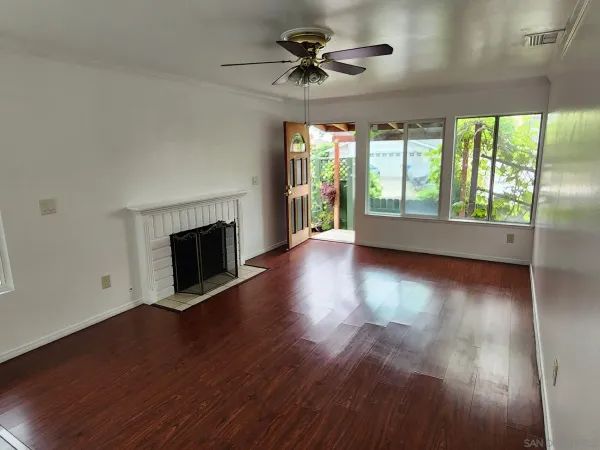 a view of empty room with wooden floor and fireplace
