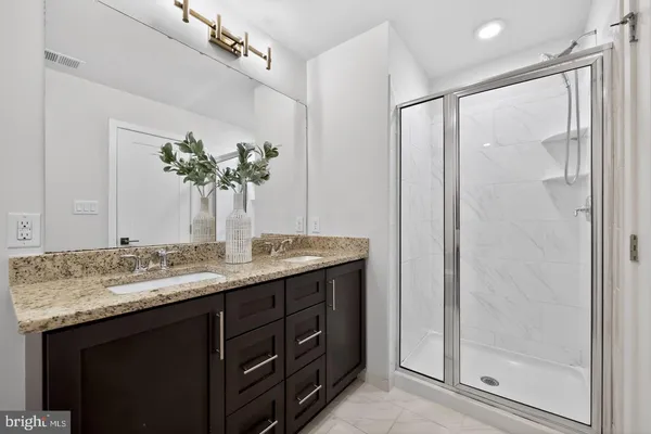 a bathroom with a granite countertop sink a mirror and a shower