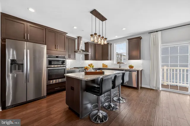 a kitchen with kitchen island granite countertop a sink cabinets a refrigerator and a stove