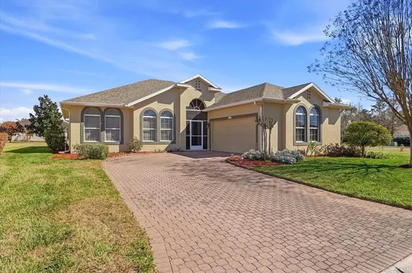 a front view of a house with a garden and trees