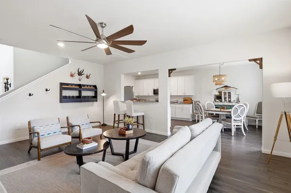 a living room with furniture kitchen view and a wooden floor