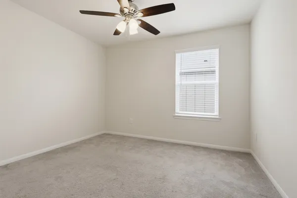 an empty room with a window and a fan