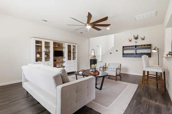 a living room with couches and kitchen view with wooden floor
