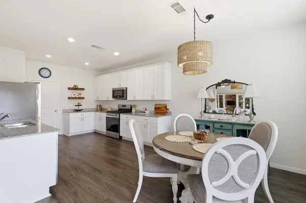 a kitchen with stainless steel appliances granite countertop a stove a sink a microwave a dining table and chairs