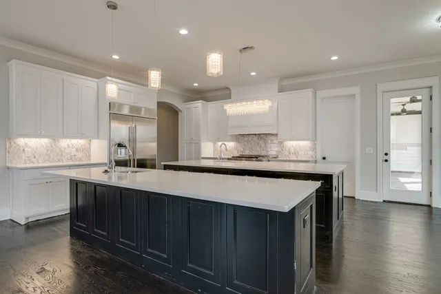 a kitchen with stainless steel appliances granite countertop a sink a stove a refrigerator and island with wooden floor