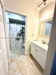 a bathroom with a granite countertop sink a toilet and shower