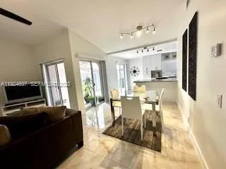 a living room with kitchen island granite countertop furniture and a flat screen tv