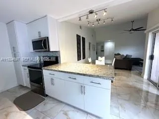 a kitchen with granite countertop a sink cabinets and stainless steel appliances