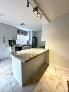 a kitchen with stainless steel appliances kitchen island granite countertop a refrigerator sink and stove