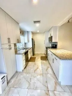 a large kitchen with stainless steel appliances kitchen island granite countertop a sink a stove top oven a counter space and cabinets
