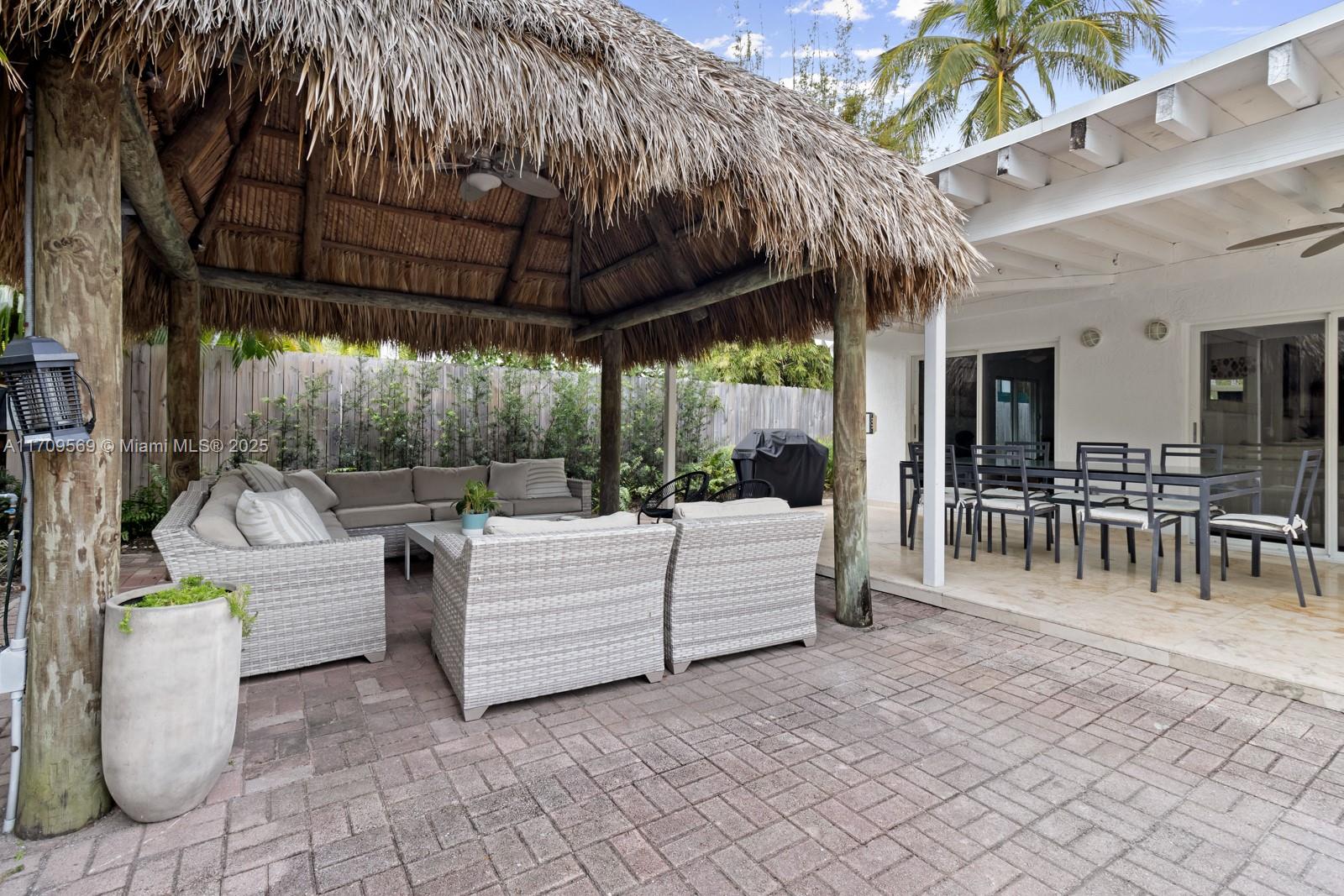 140 West Mashta Drive Key Biscayne, FL 33149 - Photo 20 of 35 a view of a patio with a dining table and chairs under an umbrella with a small yard