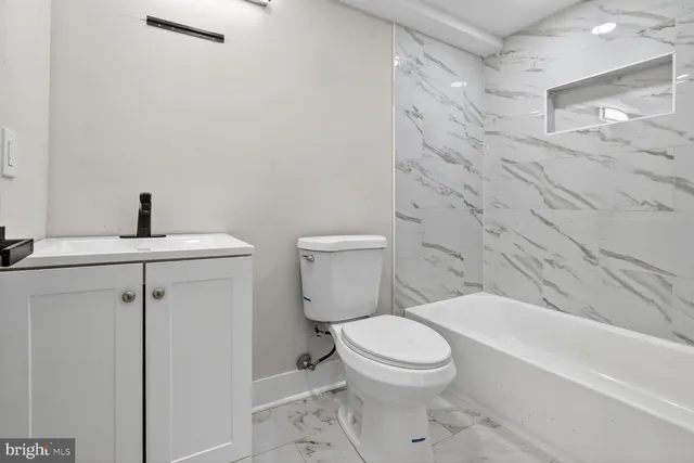 a white toilet sitting next to a bathroom sink and vanity