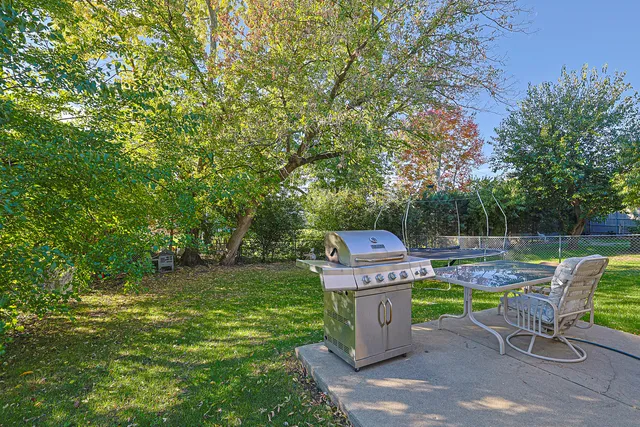 a view of a chair and table in backyard of the house