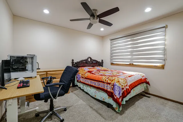 a bedroom with a bed a desk and chair with the bookshelf