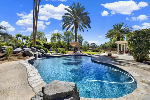 a view of a swimming pool with a lounge chair and palm trees