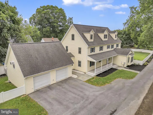 a view of a white house with a big yard plants and large trees