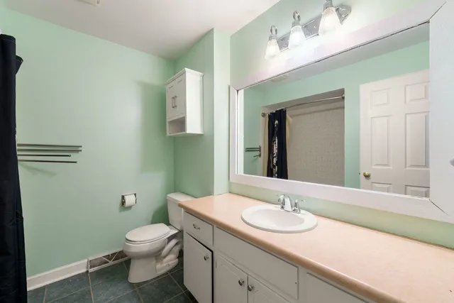 a bathroom with a granite countertop sink a toilet and a mirror