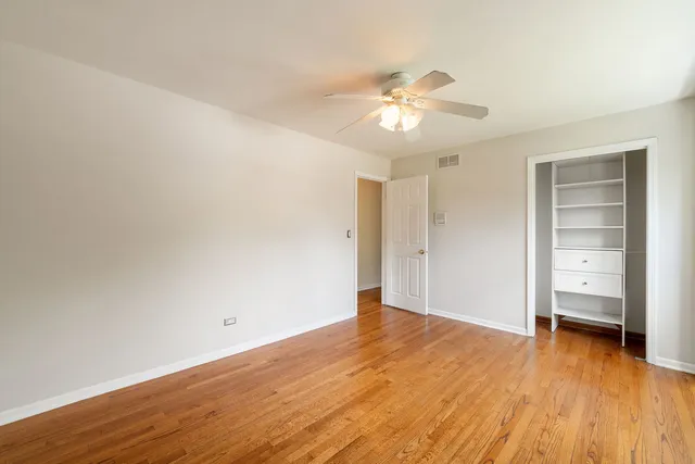 an empty room with wooden floor closet and windows