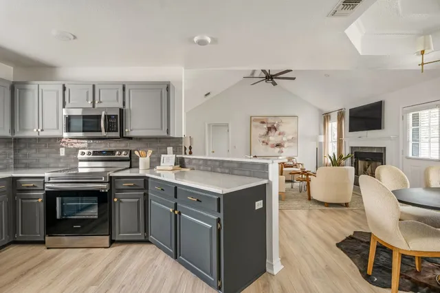 a kitchen with kitchen island granite countertop a stove top oven a sink dishwasher a dining table and chairs with wooden floor