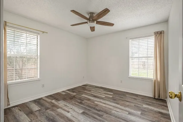 a view of empty room with wooden floor and fan