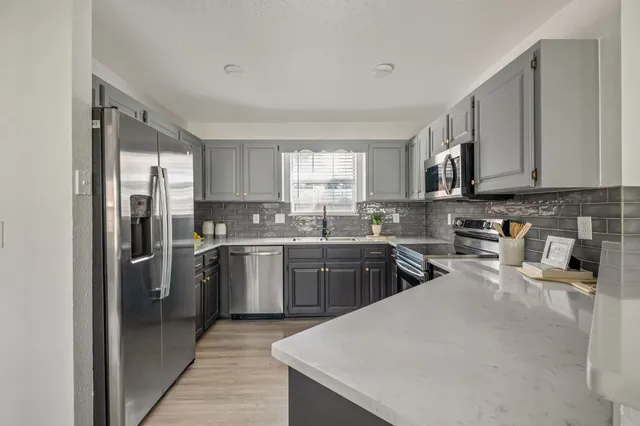 a kitchen with a refrigerator a sink a stove top oven and cabinets