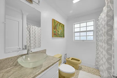 a bathroom with a granite countertop toilet sink and mirror