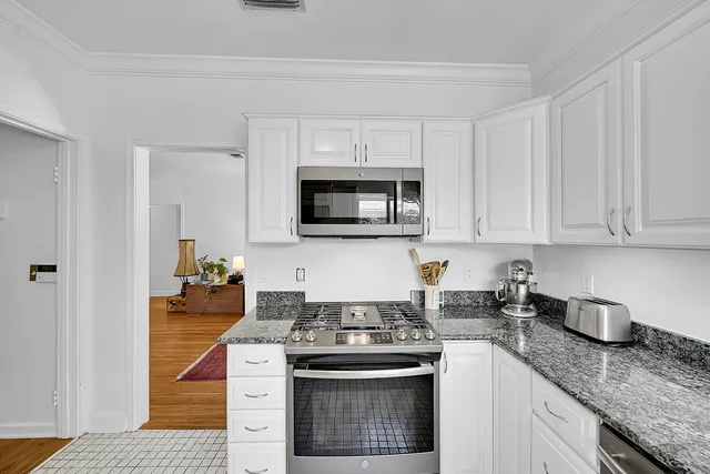 a kitchen with granite countertop white cabinets and stainless steel appliances