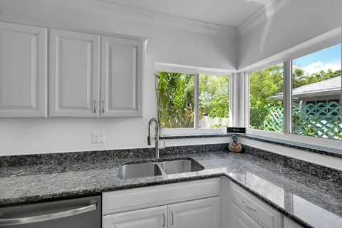 a kitchen with granite countertop a sink window and cabinets