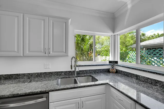 a kitchen with granite countertop a sink window and cabinets