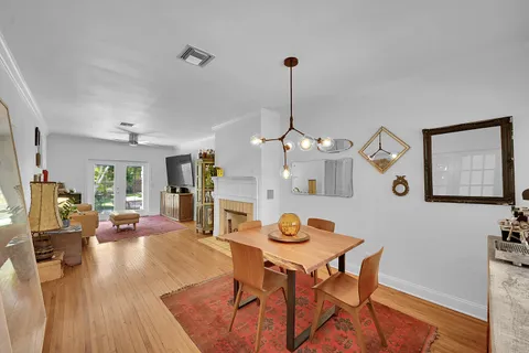 a view of a dining room and livingroom with furniture wooden floor a rug a painting and a chandelier