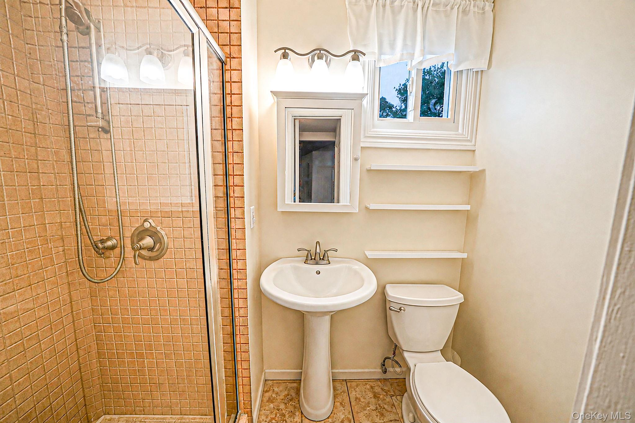 5 Rockhill Road Rocky Point, NY 11778 - Photo 21 of 48 Bathroom featuring a glass-enclosed shower with tile surround, pedestal sink, and built-in shelving