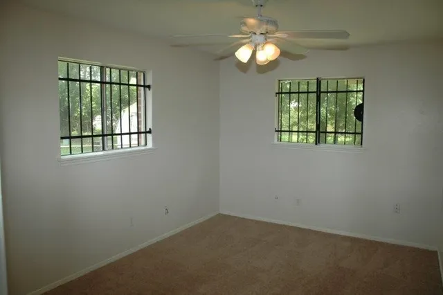 an empty room with windows and fan