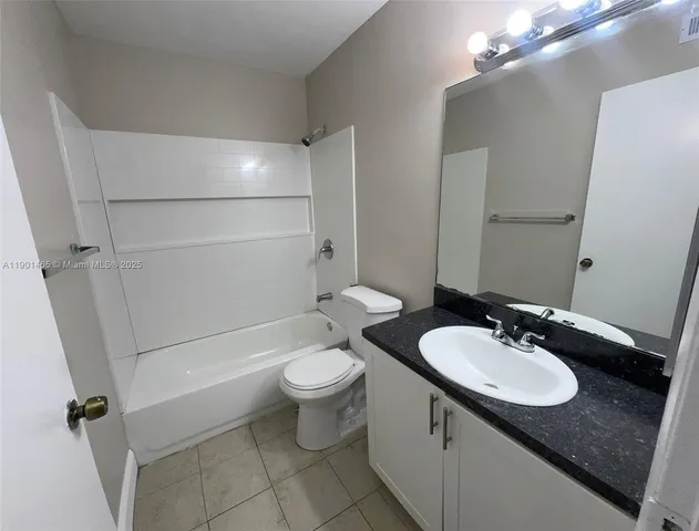 a bathroom with a granite countertop sink toilet mirror and a bathtub
