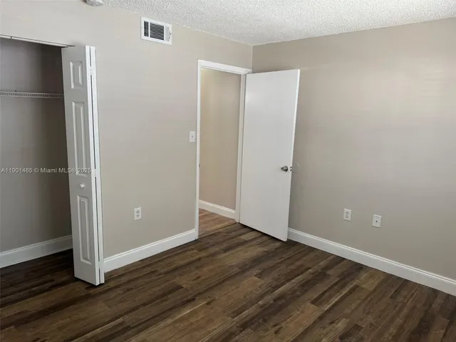 a view of an empty room with wooden floor and closet