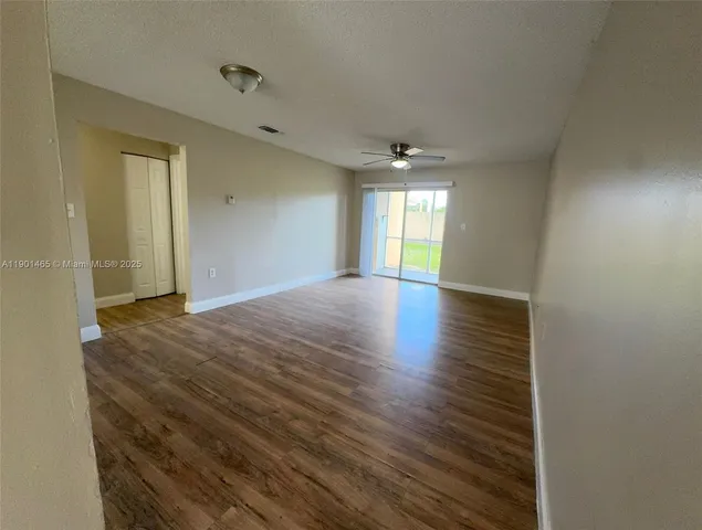 a view of an empty room with window and wooden floor