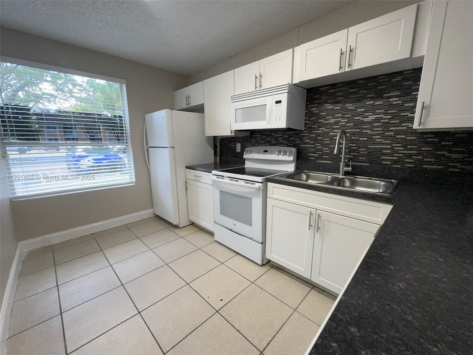 2173 Southwest 80th Terrace, Unit 2173 Miramar, FL 33025 - Photo 5 of 31 a kitchen with a stove a sink and a microwave