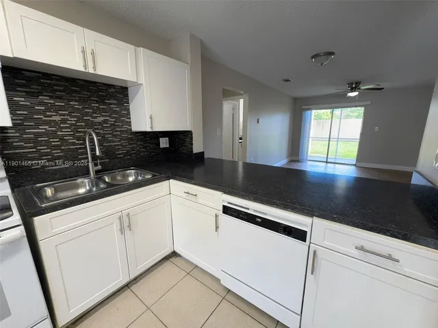 a kitchen with granite countertop white cabinets and black appliances