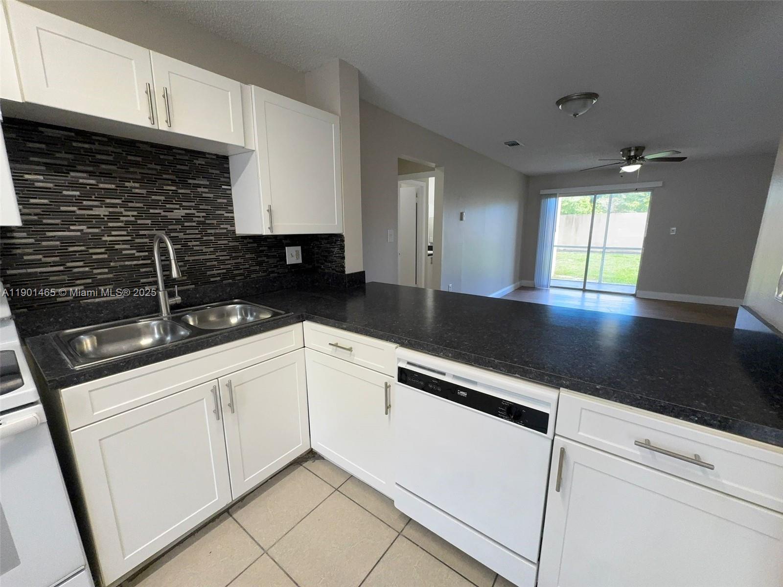 2173 Southwest 80th Terrace, Unit 2173 Miramar, FL 33025 - Photo 6 of 31 a kitchen with granite countertop white cabinets and black appliances