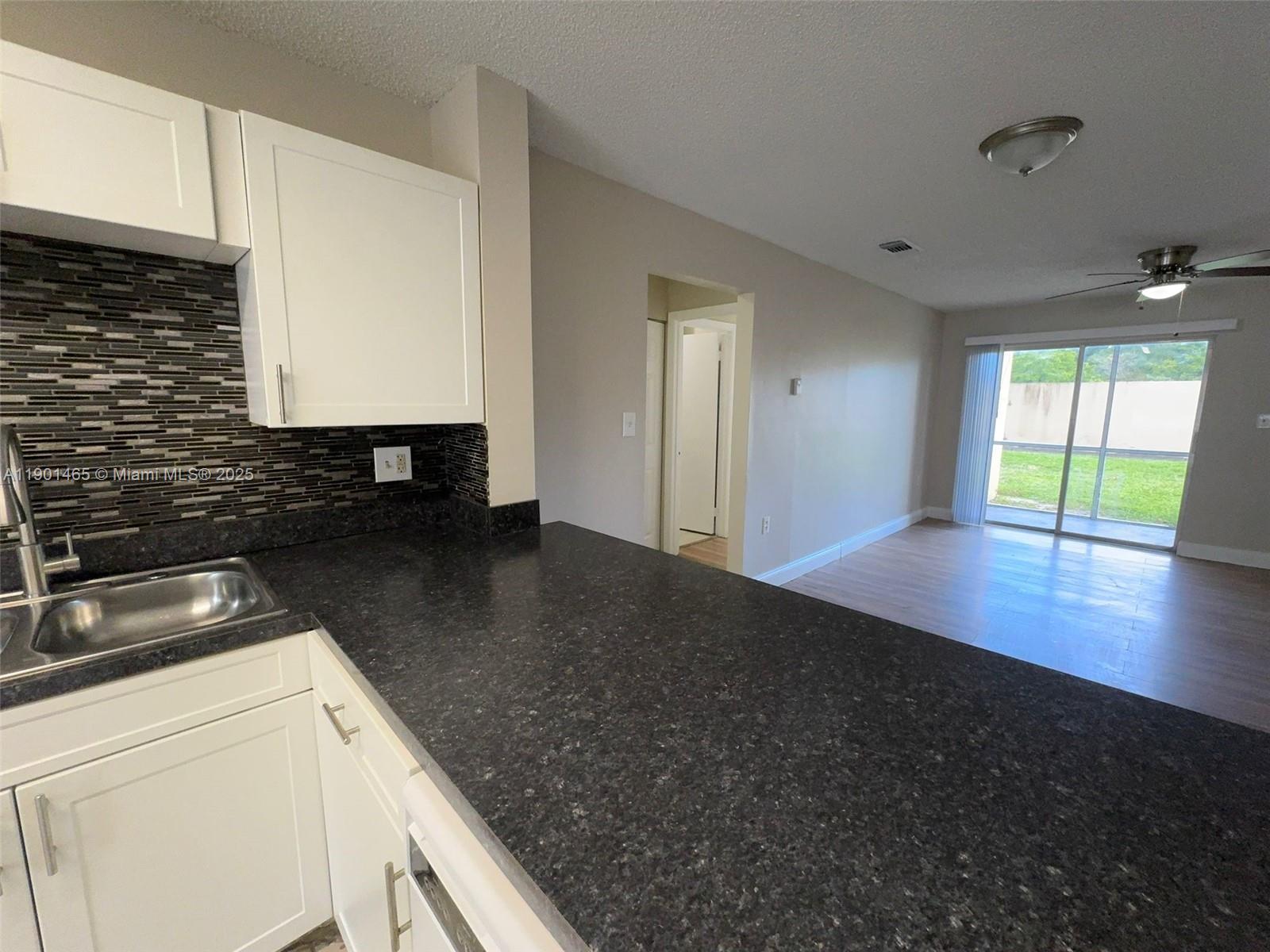 2173 Southwest 80th Terrace, Unit 2173 Miramar, FL 33025 - Photo 7 of 31 a kitchen with granite countertop a sink a stove and cabinets