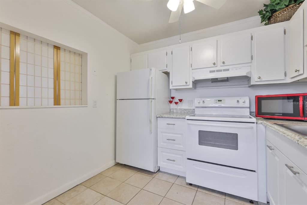 1901 Andover Way, Unit 38 Sun City Center, FL 33573 - Photo 14 of 54 a kitchen with white cabinets and white appliances
