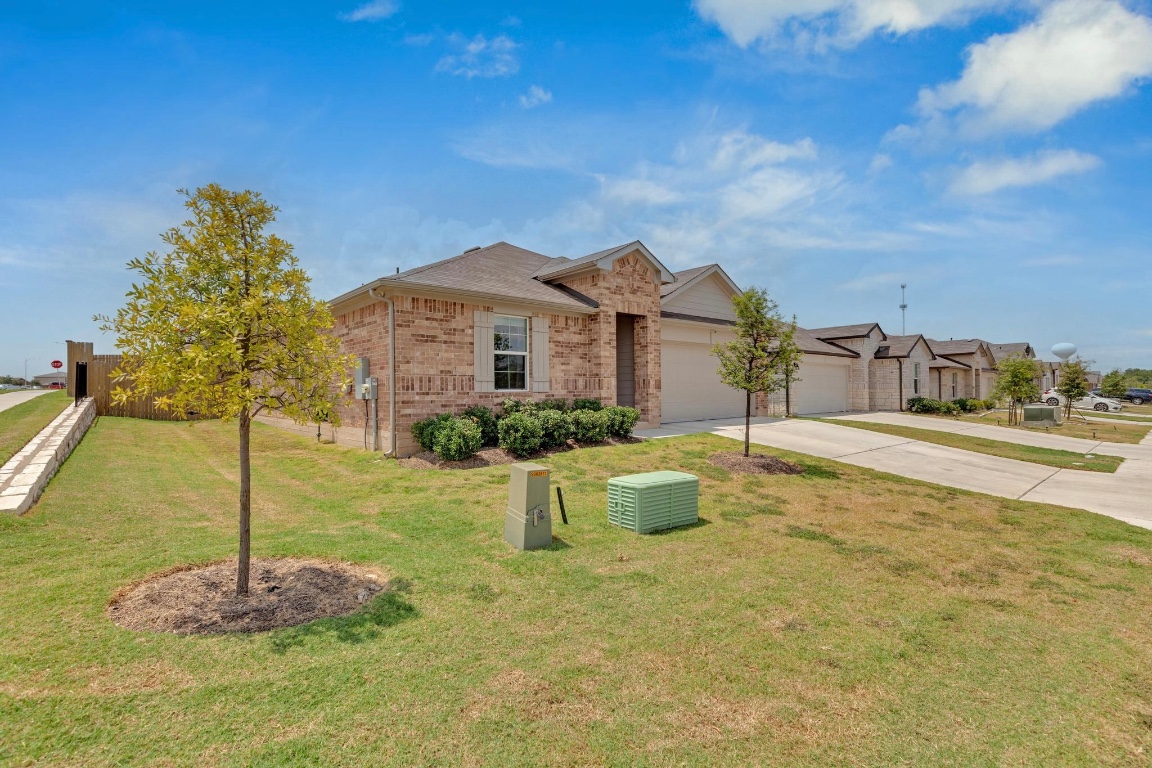 19525 Abigail Fillmore Road Manor, TX 78653 - Photo 2 of 40 Ranch-style home with concrete driveway, an attached garage, a front lawn, and brick siding