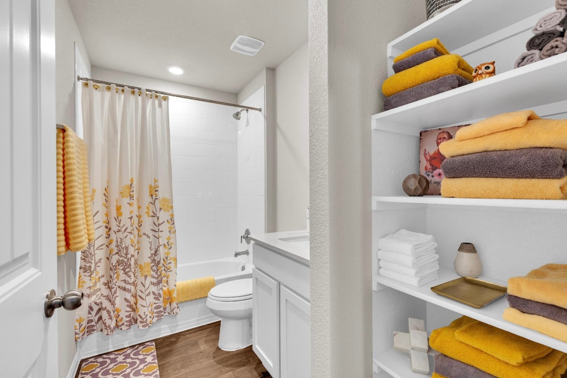 19525 Abigail Fillmore Road Manor, TX 78653 - Photo 25 of 40 Bathroom featuring shower / bath combination with curtain, vanity, and dark wood-style floors