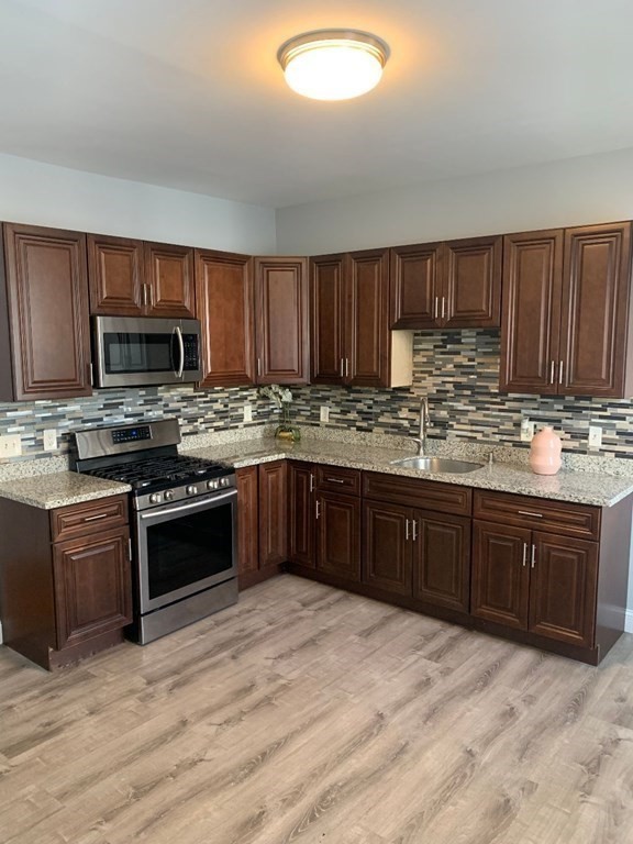 243 Bruce Street Lawrence, MA 01841 - Photo 9 of 16 a kitchen with granite countertop wooden cabinets and stainless steel appliances