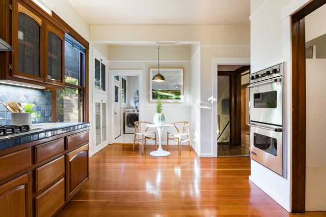 a kitchen with stainless steel appliances granite countertop a refrigerator a stove oven and white cabinets with wooden floor