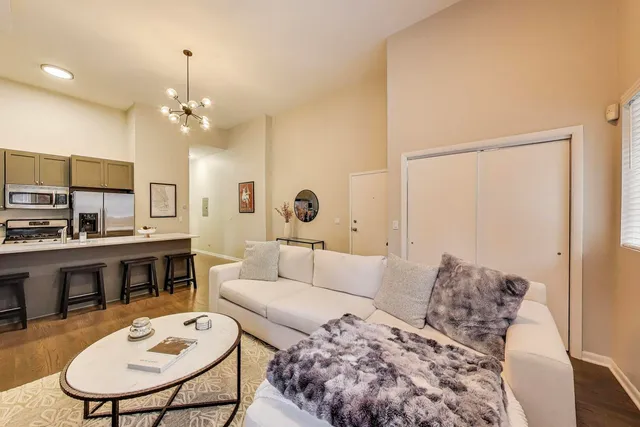 a living room with furniture potted plant and kitchen view