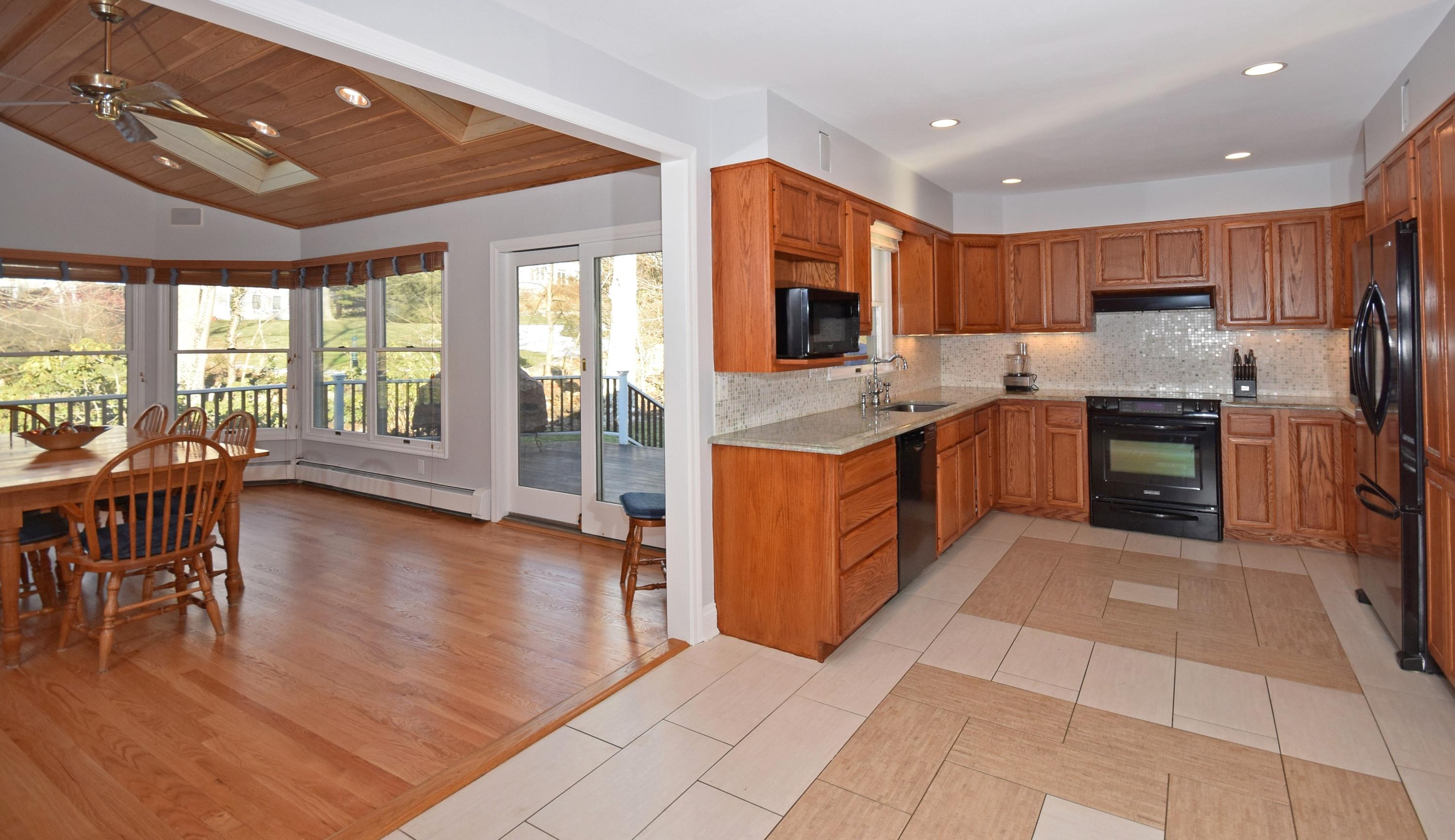 6 Wilson Ridge Road East Darien, CT 06820 - Photo 9 of 25 a kitchen with stainless steel appliances granite countertop a stove top oven a sink dishwasher a dining table and chairs with wooden floor