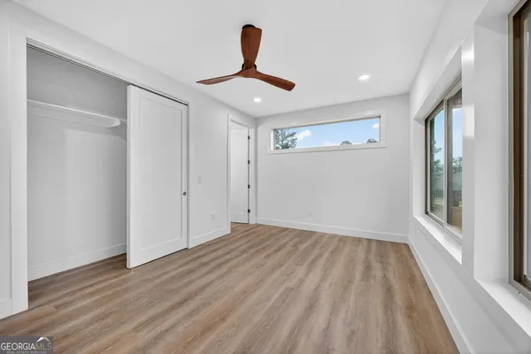 a view of empty room with wooden floor and fan